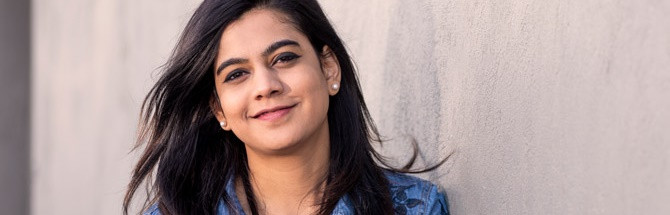 Female student smiling while learning against wall